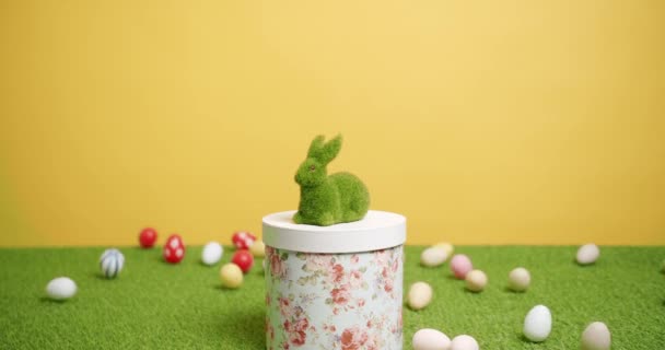 Giocattolo di coniglio su sfondo giallo di erba verde con molte uova colorate, Testo. - Filmati, video