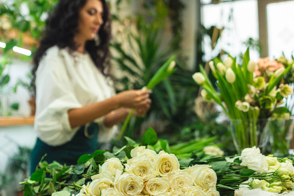 Attractive young woman florist is working in a flower shop. - Foto, imagen