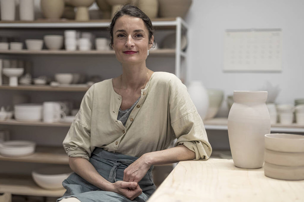 Portrait Of a Smiling Mid Adult Potter Sitting In Workshop - Foto, immagini