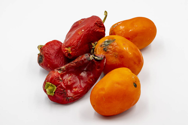 Гнилой красный перец и помидоры на белом фоне. Концепция пищевых отходов - Фото, изображение