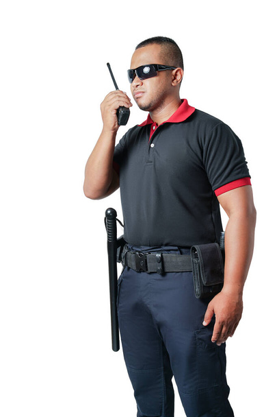Security guards in black uniforms, wearing black glasses, stand sideways and answer radios. And there are rubber batons on the tactical belt. Isolated white background. Cut out. Safety concept. - Photo, Image