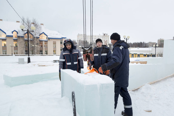 Tres trabajadores cubren el marco de un tobogán de madera con paneles de hielo - Foto, Imagen
