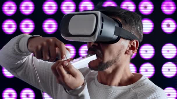 Un hombre en casco de realidad virtual enciende un cigarrillo, aprieta y tose. - Imágenes, Vídeo