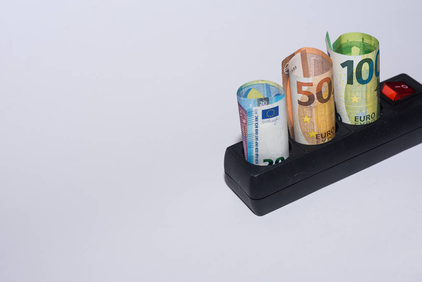 Consumo di energia e aumento dei prezzi dell'energia elettrica tre banconote in euro in un power strip vista dall'alto a destra - Foto, immagini