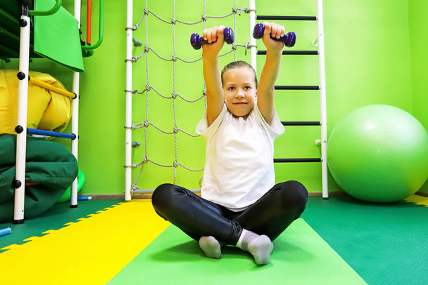 Klein meisje gaat in voor sport in speciale strakke kleren in het kindercentrum en leidt een gezonde levensstijl - Foto, afbeelding