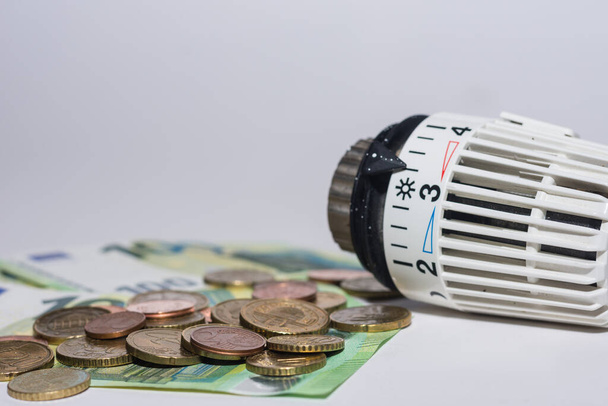 Energieprijzen stijgen en energieverbruik thermostatische regelgever van verwarming met eurobiljetten en veel munten - Foto, afbeelding