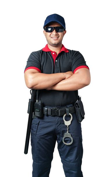 Güvenlik görevlisi siyah gözlük takıyor ve şapka takıyor. Kolları çapraz, lastik sopaları ve kelepçeleri taktik kemerlerinde duruyor. İzole edilmiş beyaz arka planda güvenlik kavramını ortadan kaldırın - Fotoğraf, Görsel