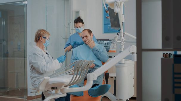 Dentysta patrząc na prześwietlenie zębów i konsultacji pacjenta z bólem zęba - Zdjęcie, obraz