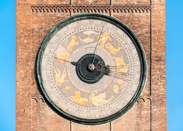 Ein riesiges ungewöhnliches Zifferblatt einer alten Uhr mit Horoskopzeichen auf einem Ziegelturm gegen den blauen Himmel - Foto, Bild