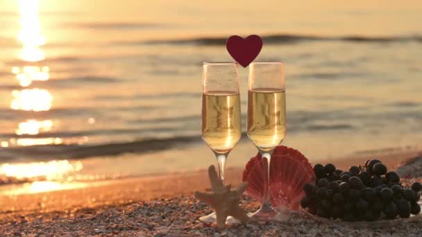 Romantyczny wieczór 14 lutego nad morzem. Kieliszki szampana o zachodzie słońca. Selektywna koncentracja na kieliszku do wina, wąska ostrość. - Materiał filmowy, wideo