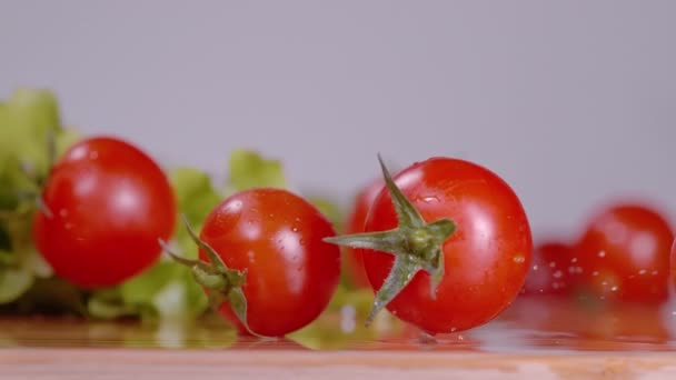 MACRO: вишневі помідори обертаються навколо мокрої дошки під час приготування салату
. - Кадри, відео