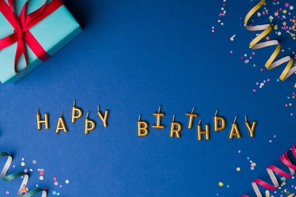 Прекрасные золотые свечи с днем рождения. Вид сверху на подарок, серпантины и разноцветные конфетти - Фото, изображение