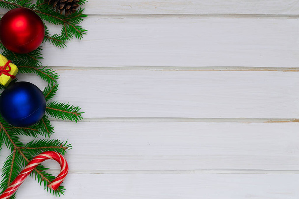 Kerst terug, grond, groene sparren takken, rode en blauwe bal, snoepjes, geschenkdoos, witte borden - Foto, afbeelding