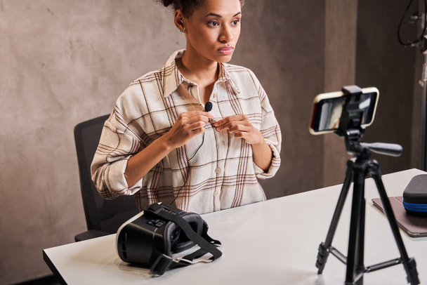 Žena vlogger vedení mikrofon na oblečení při přípravě na nahrávání svého video blogu - Fotografie, Obrázek
