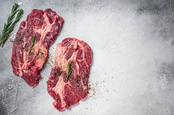Gemarmerde rauwe vlees Steaks koken met kruiden en olijfolie, verse rundvlees rib eye steaks. Witte achtergrond. Bovenaanzicht. Kopieerruimte - Foto, afbeelding
