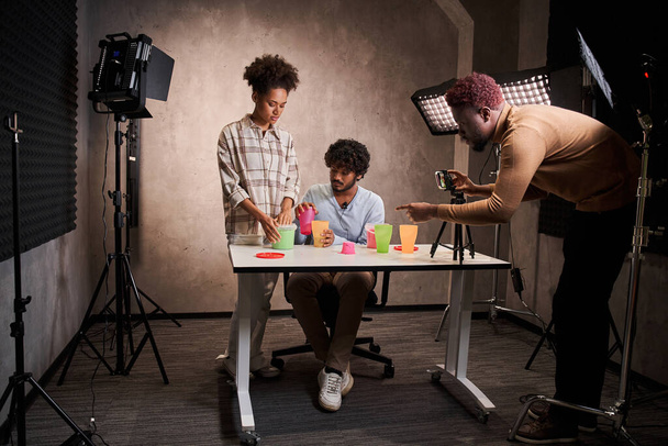 Multiracial people standing at table and preparing to live streaming with kinetic sand - Photo, image
