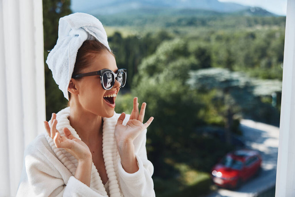 Ritratto donna che indossa occhiali da sole in posa in accappatoio su un balcone resto Mountain View - Foto, immagini
