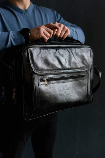 Man holding black leather travel bag. Soft light - Φωτογραφία, εικόνα