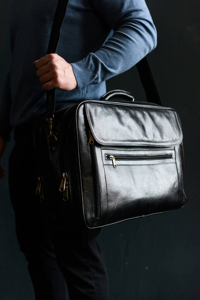 Man holding black leather travel bag. Soft light - Foto, imagen