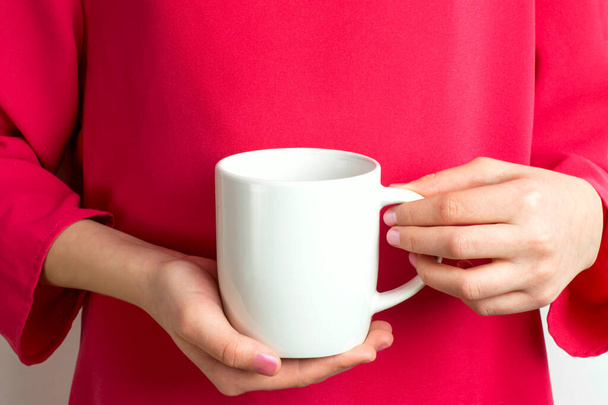 Mockup of white mug in hands of girl in red dress. Blank mug mockup for presentation and promotion design - Photo, Image