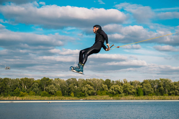 L'uomo che pratica la tecnica del salto sull'acqua con rotazione durante l'allenamento di wakeboard - Foto, immagini