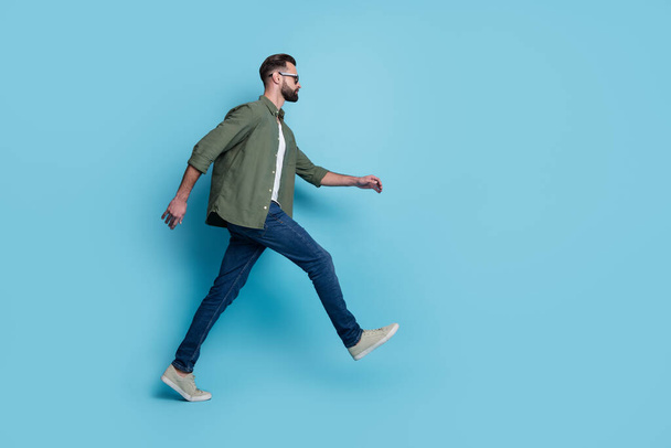 Profile photo of confident tourist guy walk wear eyeglasses green shirt jeans footwear isolated blue color background - Fotografie, Obrázek