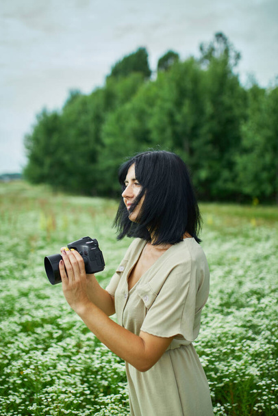 Femme photographe prendre des photos en plein air sur le paysage de champ de fleurs tenant un appareil photo, femme tenir appareil photo numérique dans ses mains. Voyage photographie de nature, espace pour le texte, vue de dessus. - Photo, image