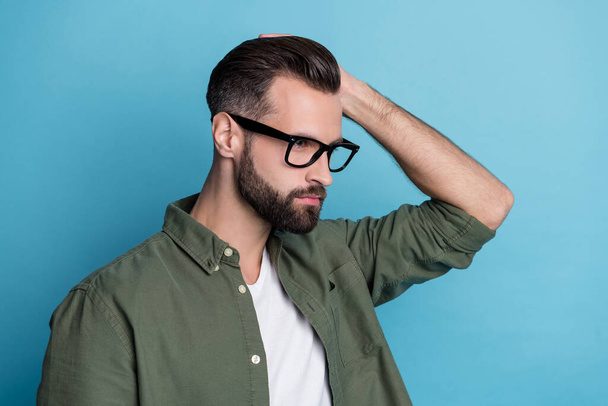 Profile photo of confident virile bearded guy hand hair look empty space wear green shirt isolated blue color background - Photo, Image
