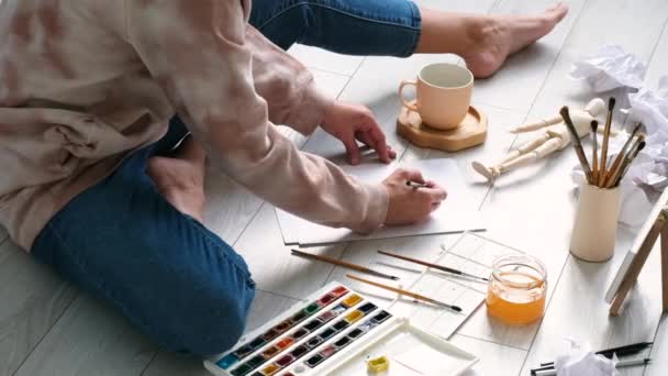 Neznámá žena maluje na plátno, sedí doma na podlaze. Domácí doučování, vzdělávání, hobby nebo volnočasová koncepce.  - Záběry, video