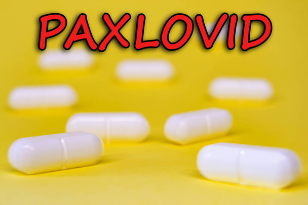Paxlovid. Antiviraal tegen Covid-19 (Coronavirus). Revolutionaire pillen voor Covid. Achtergrond met pillen op gele achtergrond. Horizontale fotografie. Ontwerp met tekst. - Foto, afbeelding