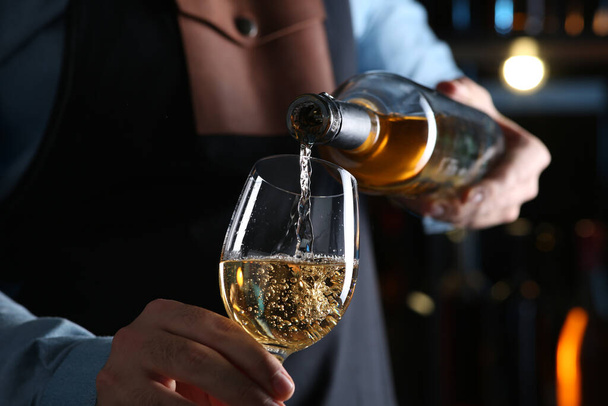 Bartender pouring white wine from bottle into glass indoors, closeup - Valokuva, kuva