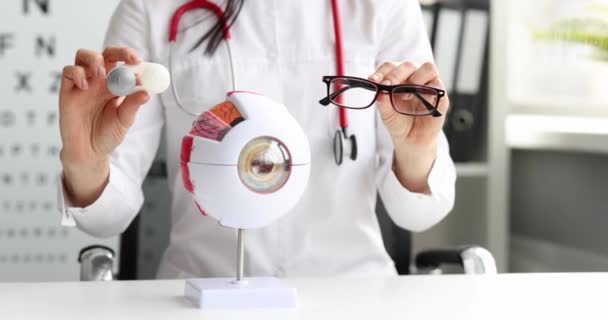 Szemész tartja szemüveg és kontaktlencse a kezében közelkép - Felvétel, videó