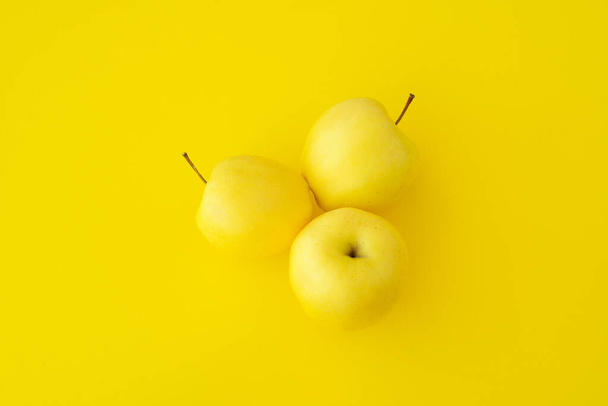 three yellow apples on a yellow background, yellow ripe fruit, fruit apple diet, yellow positive color - Foto, imagen