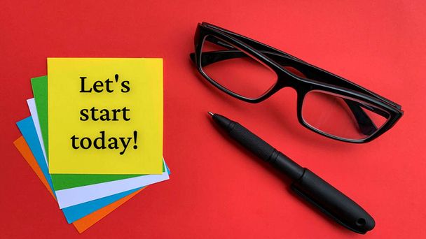 Σας επιτρέπει να ξεκινήσετε σήμερα κείμενο σε κίτρινο σημειωματάριο με γυαλιά και φόντο στυλό. Επιχειρηματική έννοια. - Φωτογραφία, εικόνα