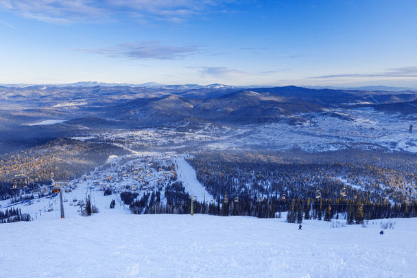 View from mount peak on Sheregesh ski resort and Altai mountains or Gornaya Shoria. Active winter rest, skiers and snowboarders on ski slope and Ski lift, nature and sport leisure. - Foto, Bild