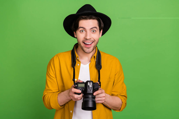 Photo of young happy excited amazed photographer paparazzi catch good shot picture isolated on green color background - Foto, afbeelding
