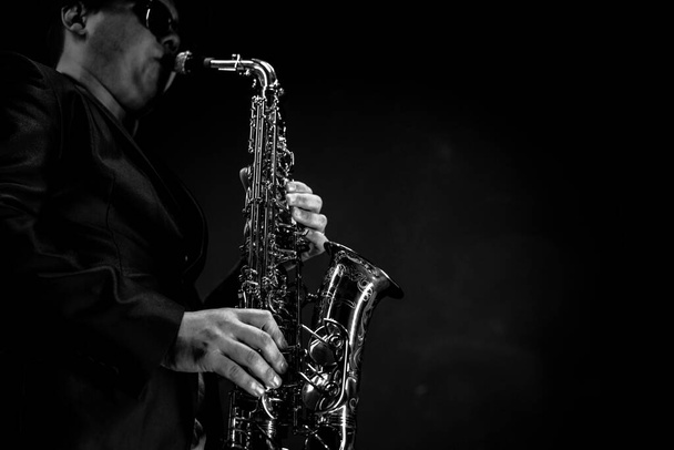 Saksofonisti Mustassa smokissa ja keula solmiossa soittaa Alto-saksofonia. Alto Sax Player, jazzsaksofonisti. Mustaa taustaa. Lähemmäs. Kopioi tila  - Valokuva, kuva