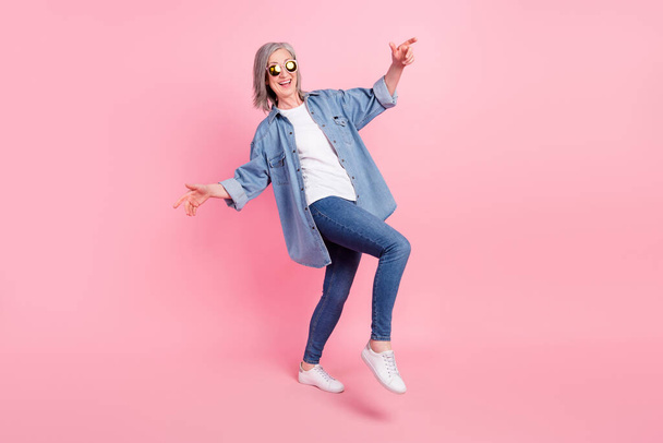 Full body photo of crazy aged lady dance wear blue blazer jeans sneakers isolated on pink color background - Foto, Imagem