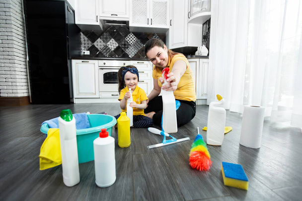 Mom and daughter are ready to clean the apartment, spraying detergent from the spray gun - 写真・画像