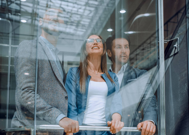 Business people in a large glass elevator in a modern office - Фото, зображення