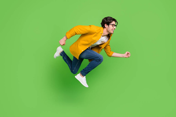 Full size profile side photo of young handsome man running in air fast speed isolated on green color background - Foto, Imagem