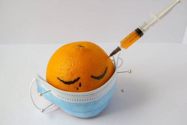 máscara médica fixada com agulhas a uma laranja - Foto, Imagem
