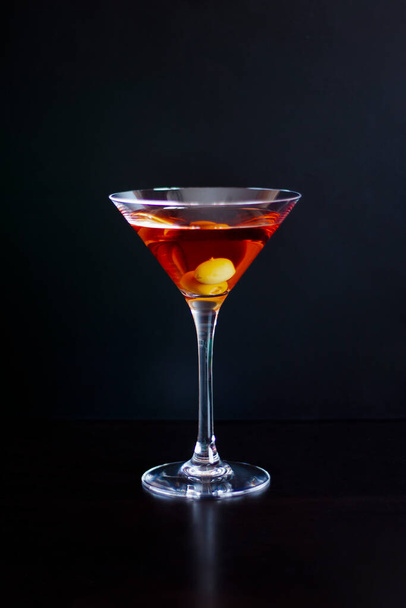 Koyu arkaplanda zeytinli bir bardak kırmızı martini. dikey resim - Fotoğraf, Görsel