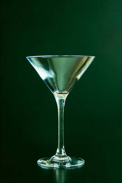 Пустой бокал мартини на зеленом фоне. вертикальное фото - Фото, изображение