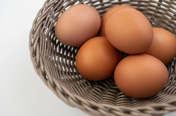 Closeup of fresh brown eggs in Easter basket over white background - Foto, immagini