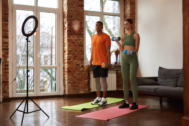 Couple do exercise with dumbbells for sport video - Zdjęcie, obraz