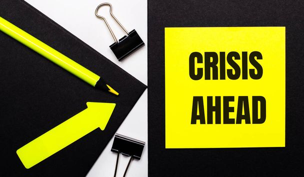 On a black background, a bright yellow pencil and an arrow and a yellow sheet of paper with the text CRISIS AHEAD - Fotoğraf, Görsel