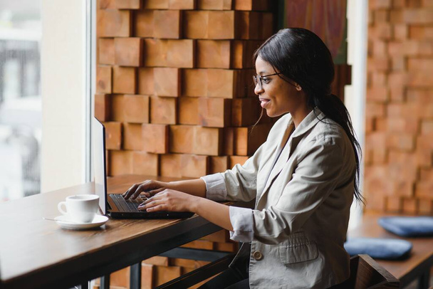 Jeune femme d'affaires afro-américaine focalisée ou étudiant regardant un ordinateur portable, femme noire sérieuse travaillant ou étudiant avec un ordinateur faisant de la recherche ou se préparant à l'examen en ligne - Photo, image