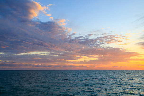 naplemente a tengeren, cirrus felhők naplementekor. este a tengeren, a horizont vonal naplementekor - Fotó, kép