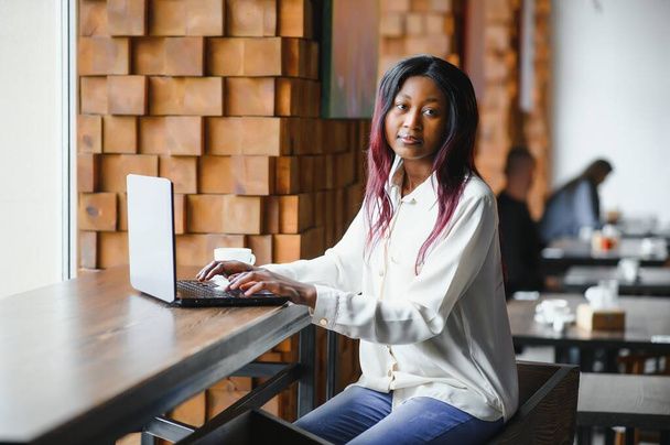 Happy african american woman worker using laptop work study at computer in loft office or cafe, smiling mixed race female student freelancer using pc app dating communicating online watching webinar - Foto, Imagem